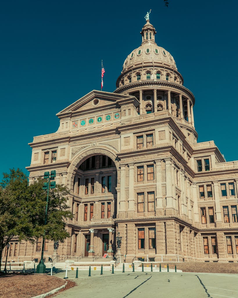 Historical Texas State Capitol against a clear blue sky on a sunny day in Austin, TX.