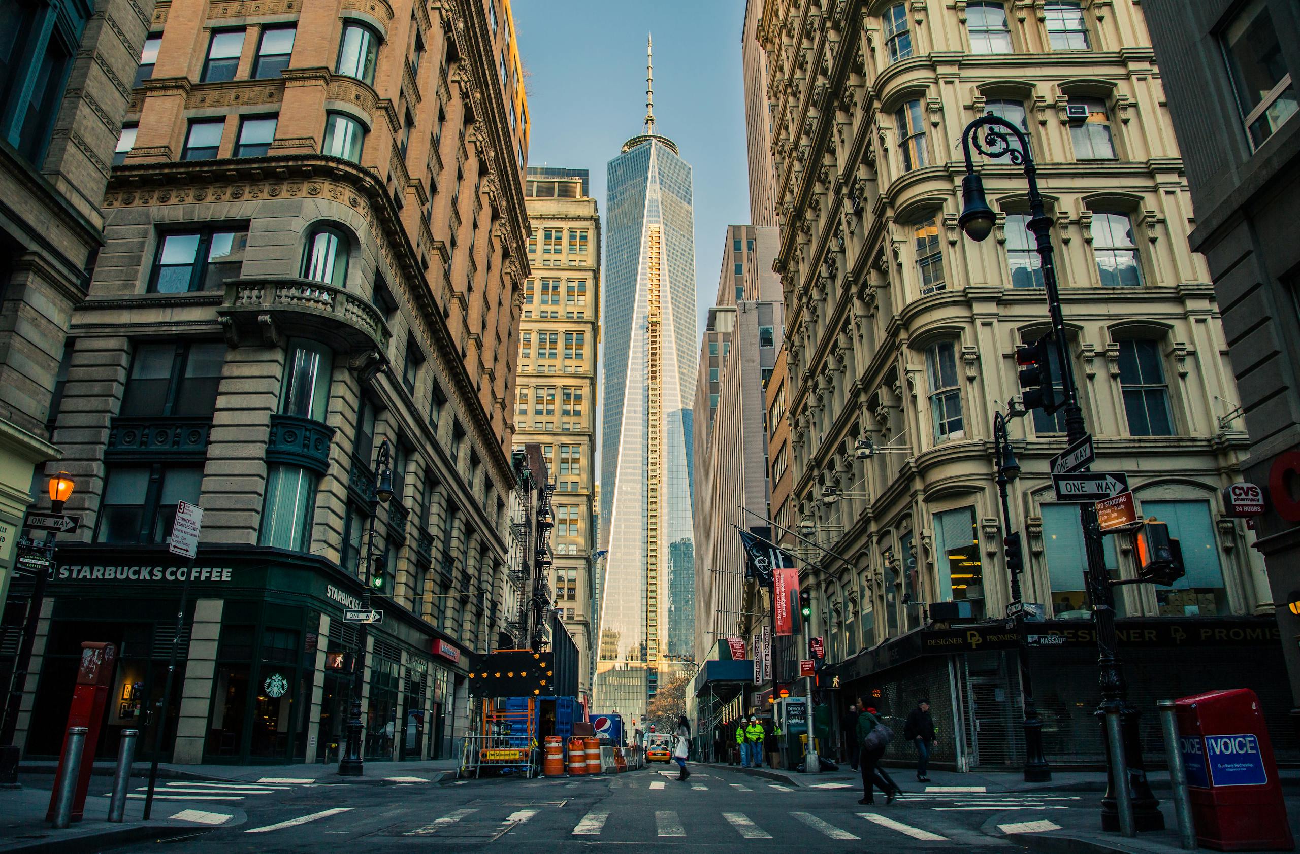 Street view of One World Trade Center in New York City surrounded by urban architecture and city life. Get the best new york group hotel rates from hotel rates direct. 