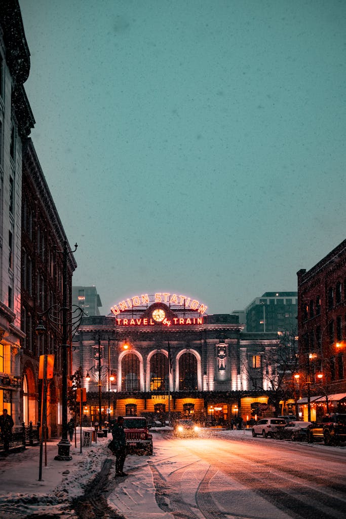 Union Station illuminated in a snowy Denver evening, showcasing urban life and winter weather.
