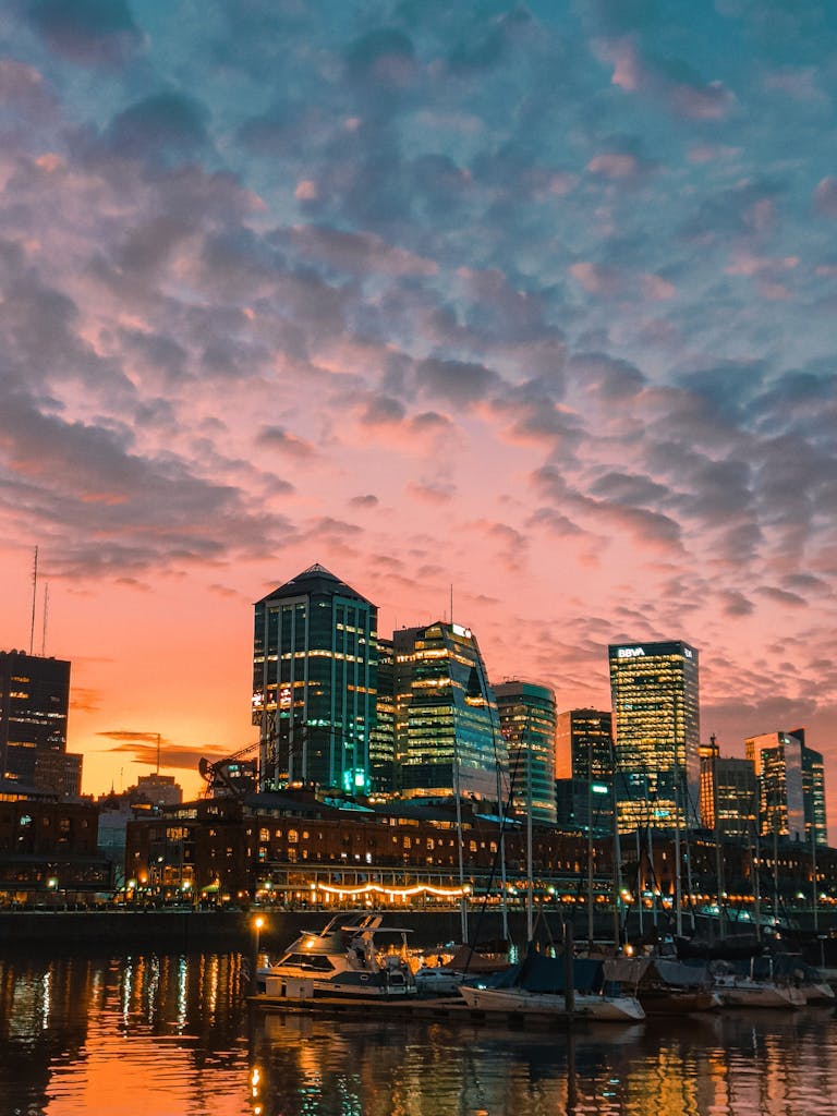 Vibrant city skyline with moored yachts during a stunning sunset by the marina.