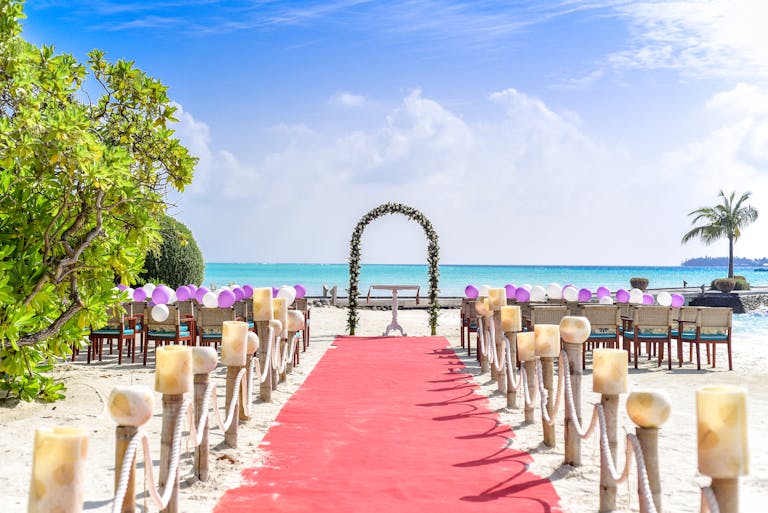 A scenic tropical beach wedding setup with a red carpet aisle and ocean views, perfect for destination weddings. HRD will help you find a hotel block for wedding.